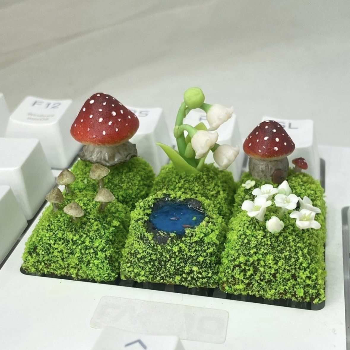 Handcrafted Mushroom Keycap Set Step into a whimsical world with our Handmade Mushroom Keycap Set, where mushrooms thrive on a bed of lush moss, adding an enchanting touch to your keyboard. Mystical Details: Each keycap is a testament to craftsmanship, meticulously created to resemble the beauty of nature. These tiny mushrooms sprout from a bed of moss, making your keyboard a portal to a fairy tale realm.