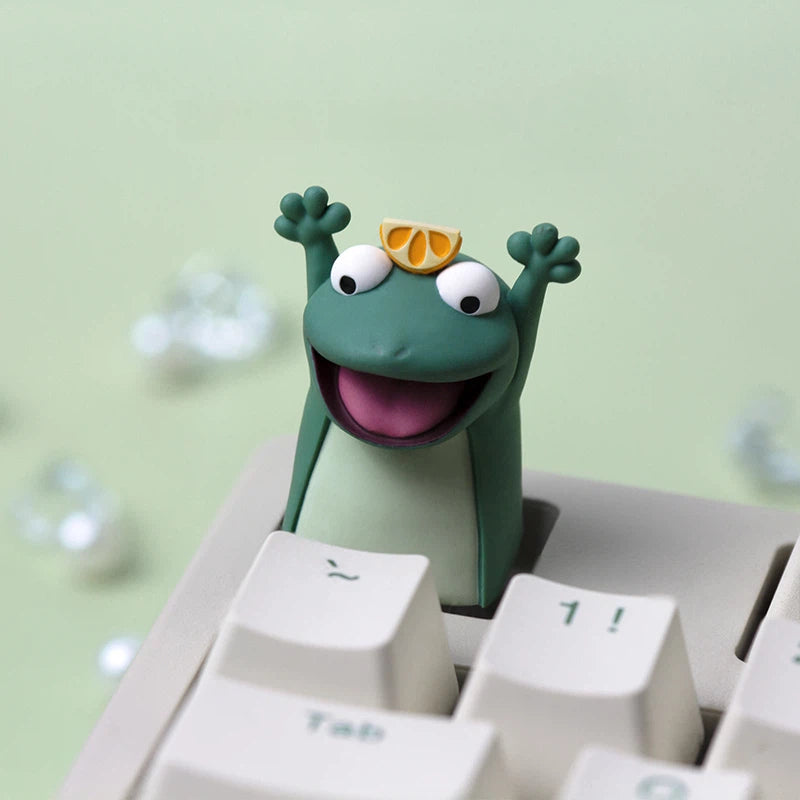 Adorable frog artisan keycap set including Flower Frog, Lemon Frog, and Waving Frog designs. Each keycap is created with layered epoxy resin techniques and hand polishing to showcase cute expressions and detailed character styling.