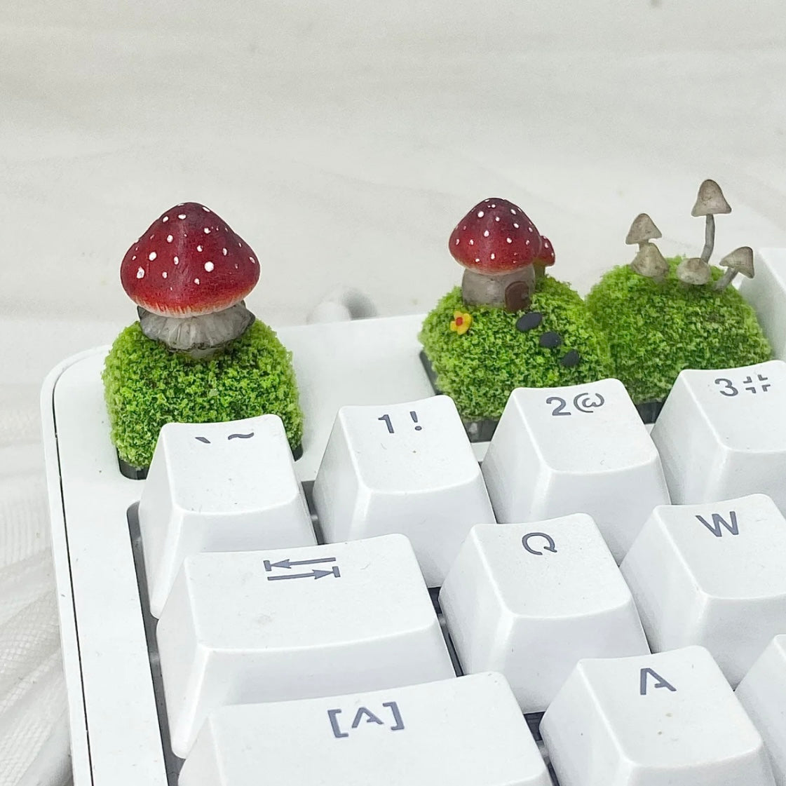 Handcrafted Mushroom Keycap Set  Step into a whimsical world with our Handmade Mushroom Keycap Set, where mushrooms thrive on a bed of lush moss, adding an enchanting touch to your keyboard.  Mystical Details:  Each keycap is a testament to craftsmanship, meticulously created to resemble the beauty of nature. These tiny mushrooms sprout from a bed of moss, making your keyboard a portal to a fairy tale realm.