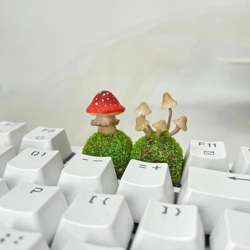 Handcrafted Mushroom Keycap Set  Step into a whimsical world with our Handmade Mushroom Keycap Set, where mushrooms thrive on a bed of lush moss, adding an enchanting touch to your keyboard.  Mystical Details:  Each keycap is a testament to craftsmanship, meticulously created to resemble the beauty of nature. These tiny mushrooms sprout from a bed of moss, making your keyboard a portal to a fairy tale realm.