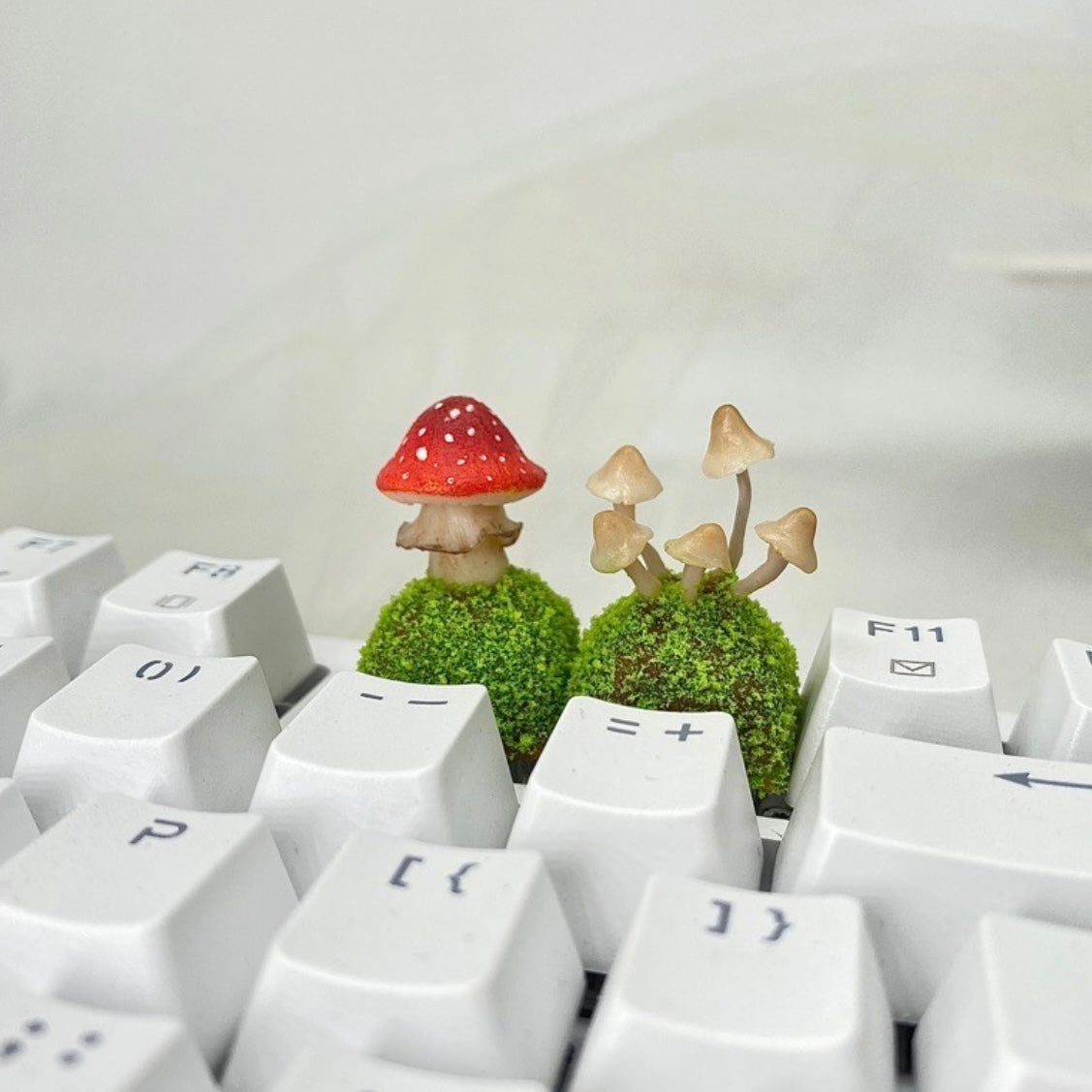 Handcrafted Mushroom Keycap Set  Step into a whimsical world with our Handmade Mushroom Keycap Set, where mushrooms thrive on a bed of lush moss, adding an enchanting touch to your keyboard.  Mystical Details:  Each keycap is a testament to craftsmanship, meticulously created to resemble the beauty of nature. These tiny mushrooms sprout from a bed of moss, making your keyboard a portal to a fairy tale realm.