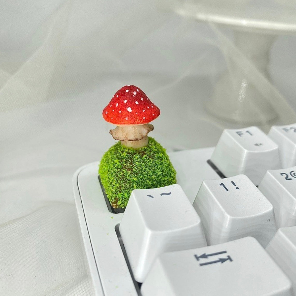 Handcrafted Mushroom Keycap Set  Step into a whimsical world with our Handmade Mushroom Keycap Set, where mushrooms thrive on a bed of lush moss, adding an enchanting touch to your keyboard.  Mystical Details:  Each keycap is a testament to craftsmanship, meticulously created to resemble the beauty of nature. These tiny mushrooms sprout from a bed of moss, making your keyboard a portal to a fairy tale realm.