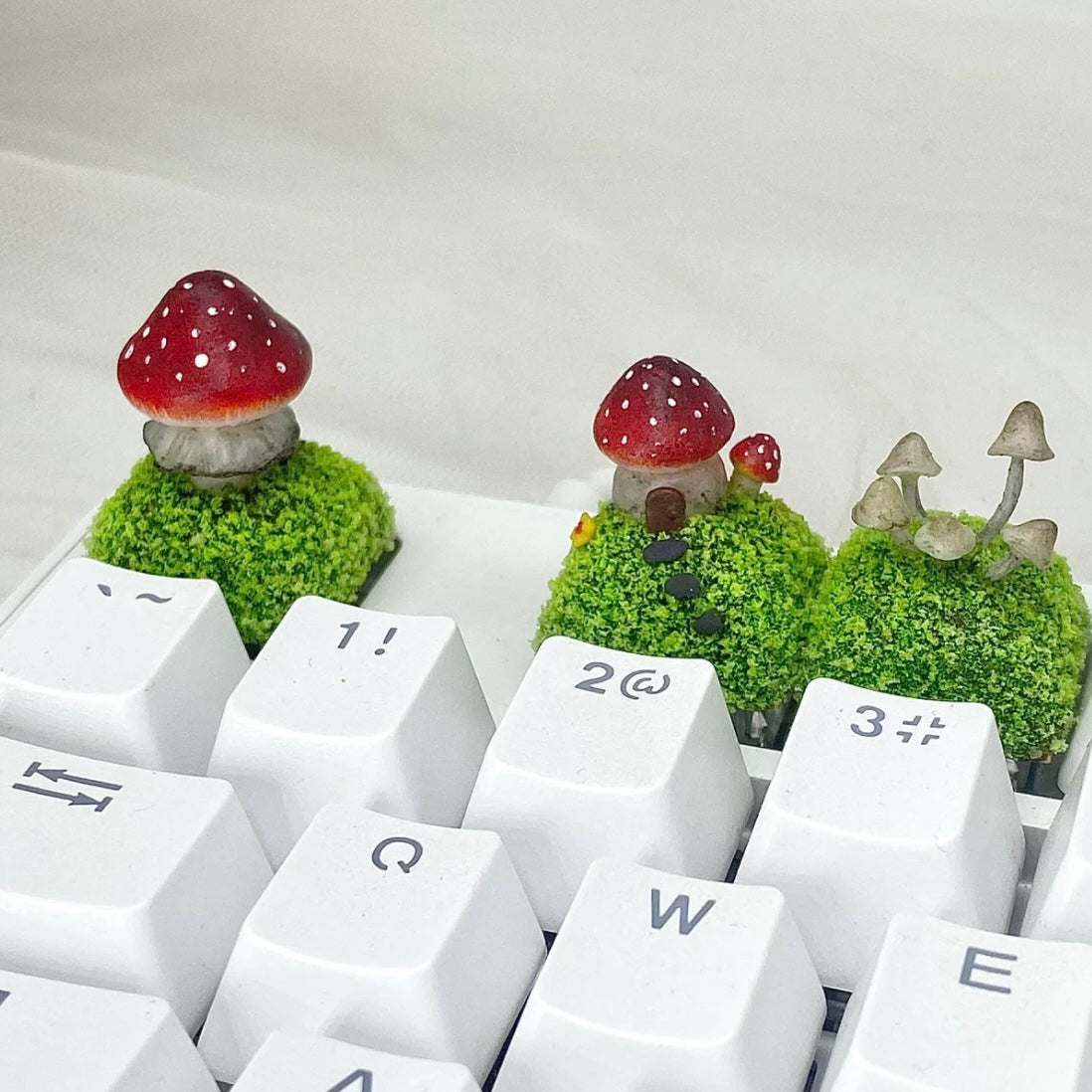 Handcrafted Mushroom Keycap Set  Step into a whimsical world with our Handmade Mushroom Keycap Set, where mushrooms thrive on a bed of lush moss, adding an enchanting touch to your keyboard.  Mystical Details:  Each keycap is a testament to craftsmanship, meticulously created to resemble the beauty of nature. These tiny mushrooms sprout from a bed of moss, making your keyboard a portal to a fairy tale realm.