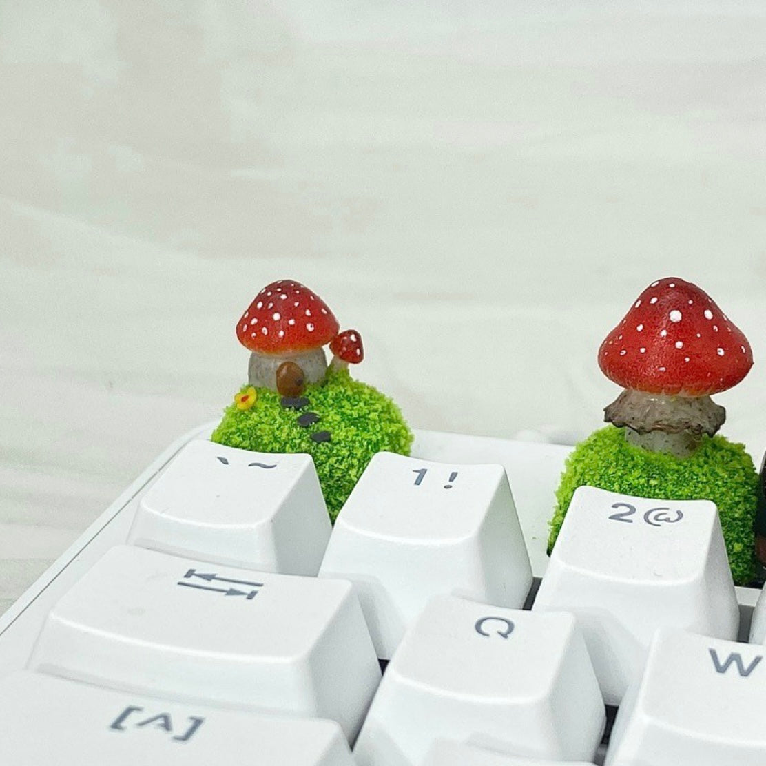 Handcrafted Mushroom Keycap Set  Step into a whimsical world with our Handmade Mushroom Keycap Set, where mushrooms thrive on a bed of lush moss, adding an enchanting touch to your keyboard.  Mystical Details:  Each keycap is a testament to craftsmanship, meticulously created to resemble the beauty of nature. These tiny mushrooms sprout from a bed of moss, making your keyboard a portal to a fairy tale realm.