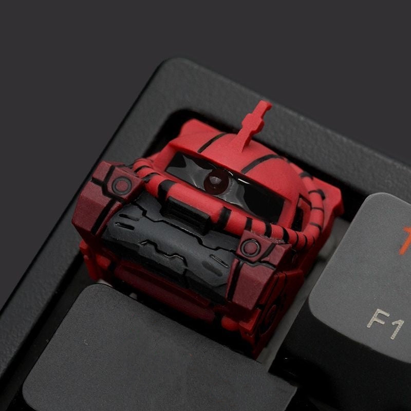 Mobile Suit Gundam-themed artisan keycap in red or green Zaku II style for mechanical keyboards.
